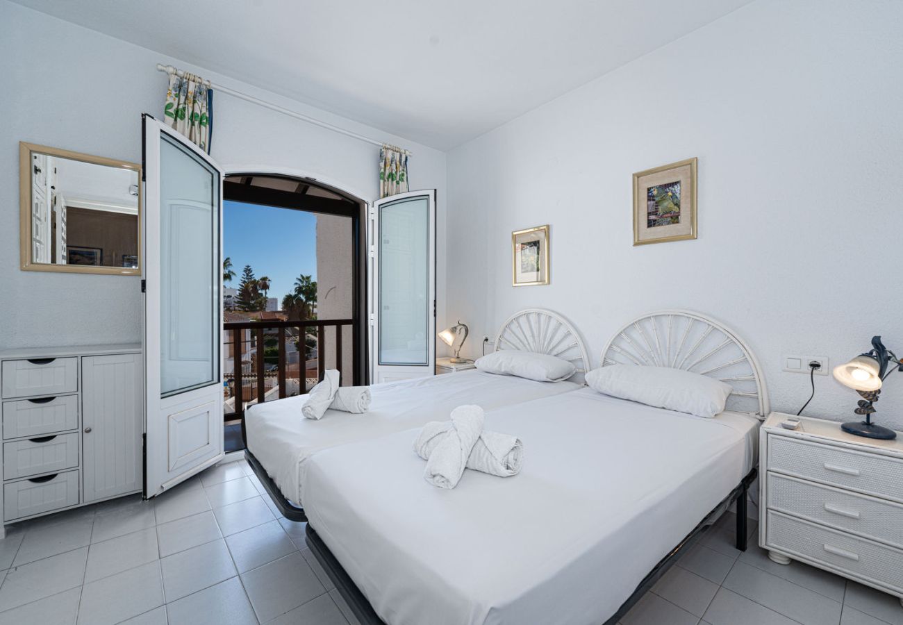 Dormitorio con camas individuales y ventana al exterior en casa adosada en Nerja.