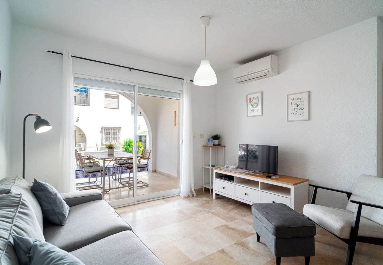 Salón luminoso con sofá moderno y acceso a la terraza en el centro de Nerja.