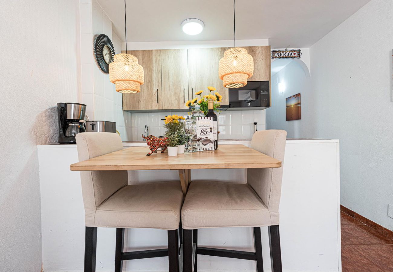 Zona de comedor con cocina abierta y pack de bienvenida Casasol con vino y chocolate.