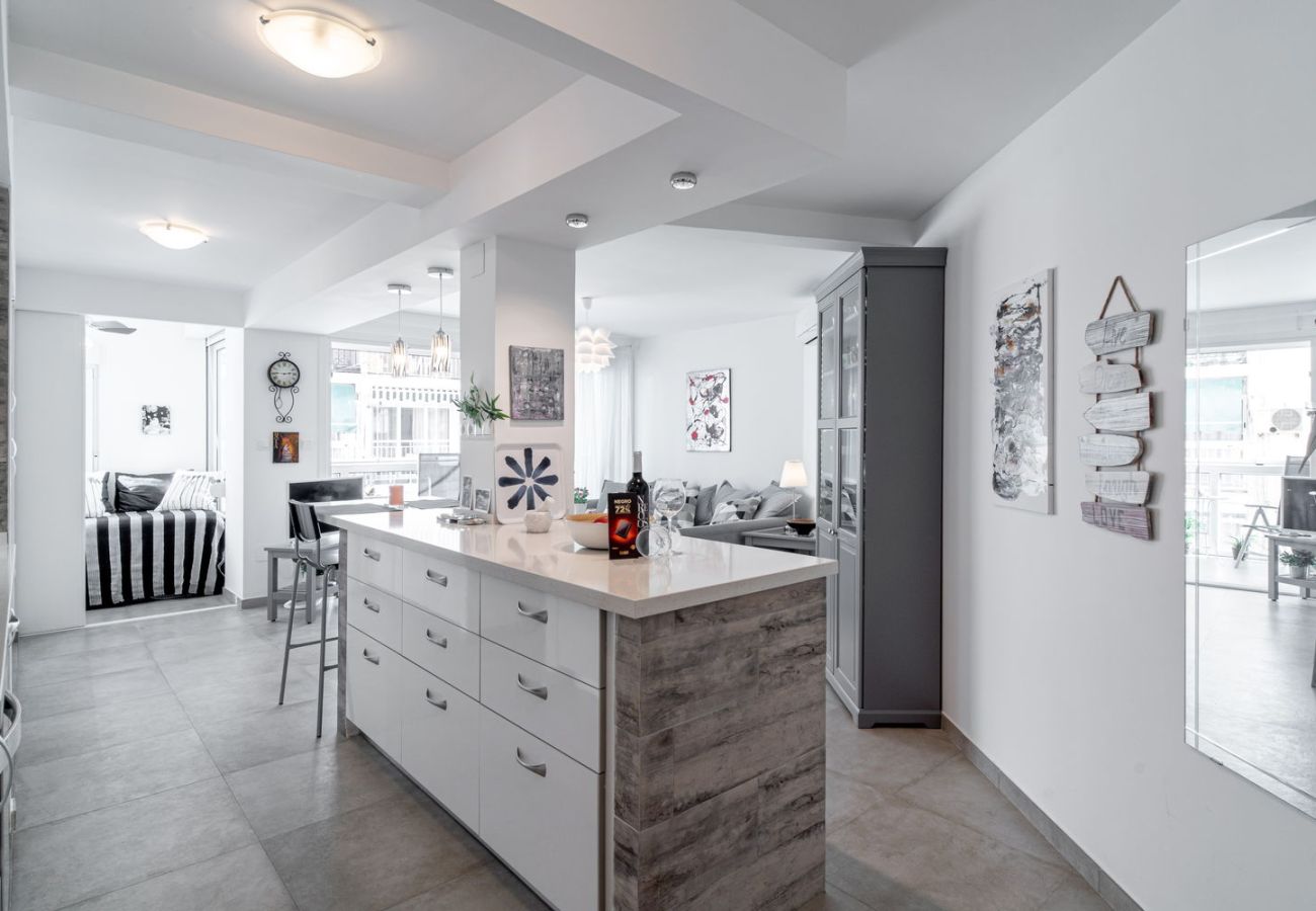 Zona de comedor con mesa de madera y sillas de diseño junto a cocina equipada en Nerja.