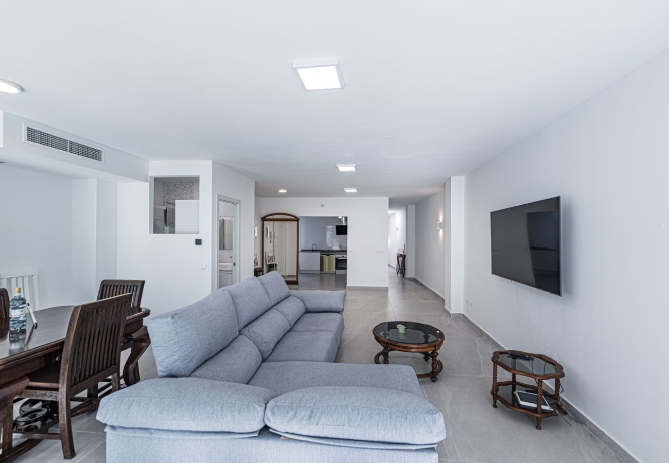 Salón amplio y luminoso con sofás y televisión en apartamento en el centro de Nerja.