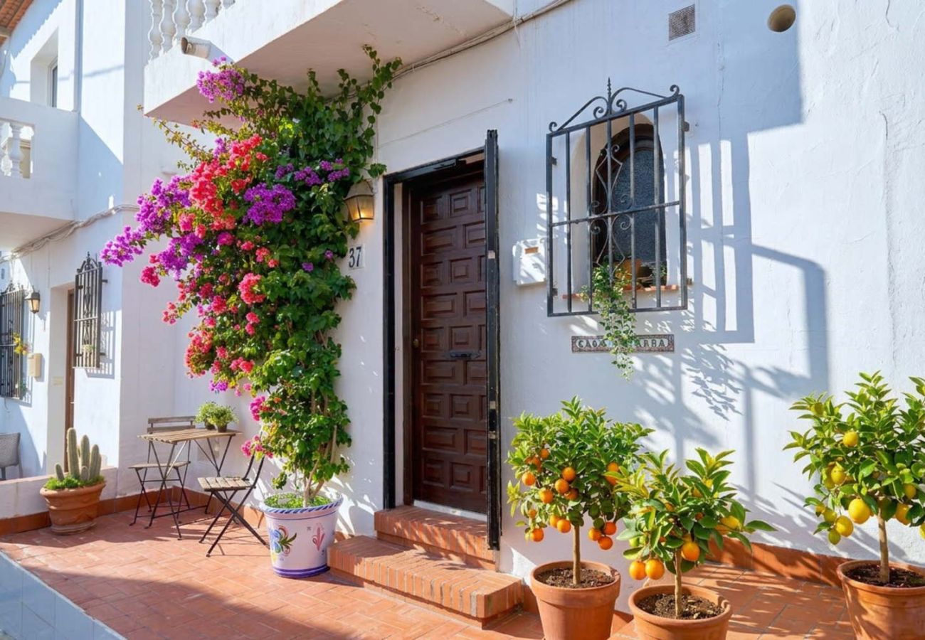 Entrada principal de la casa en La Hacienda con flores y estilo tradicional andaluz.