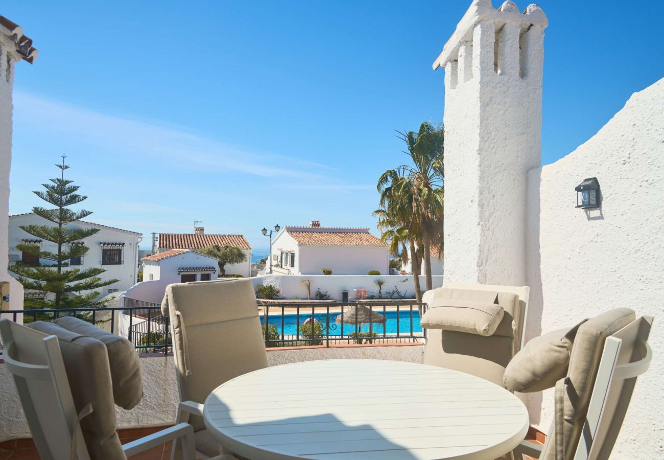 Terraza privada en Capistrano Village Nerja con mesa de comedor y vistas a la piscina comunitaria.